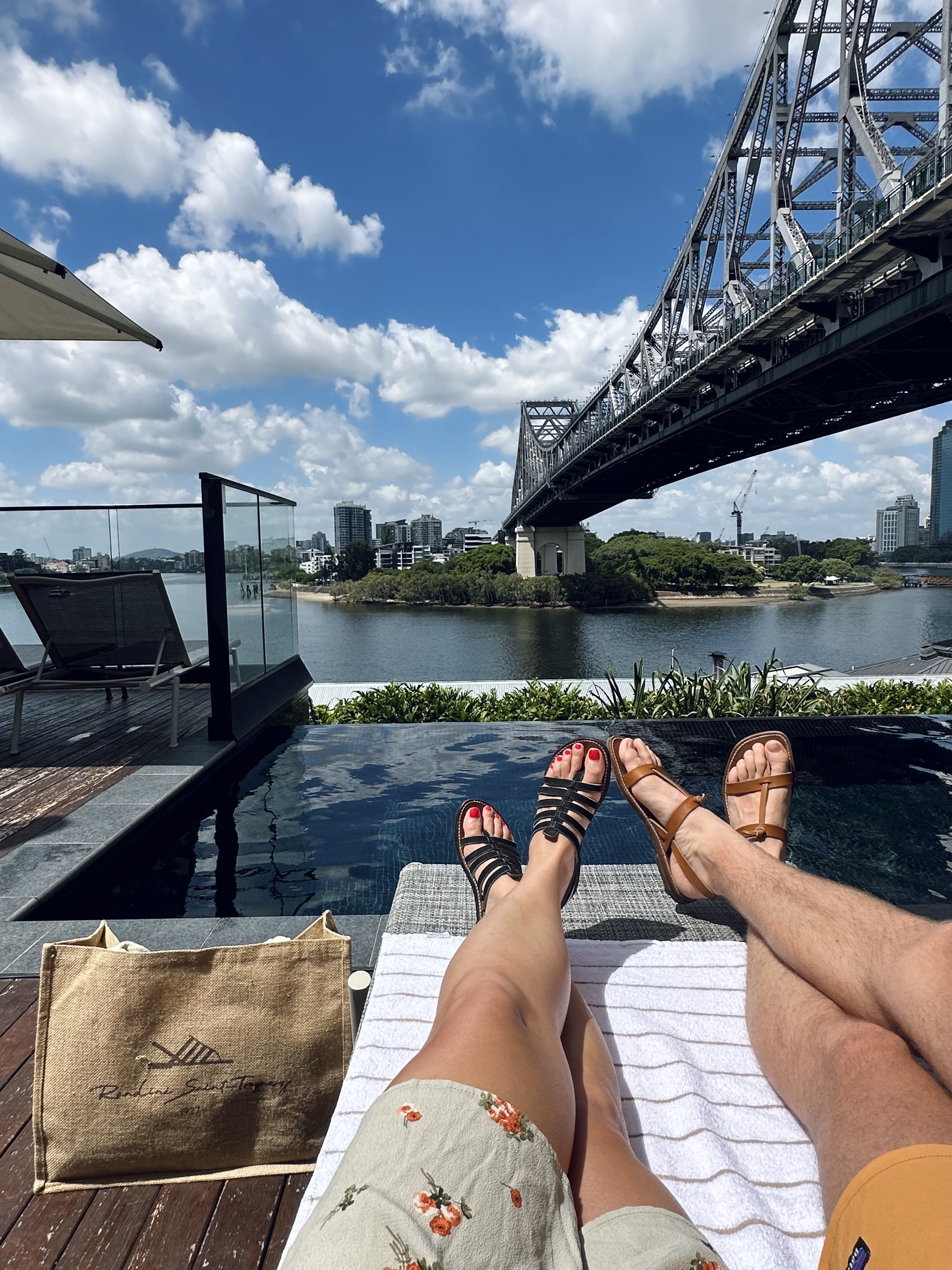 pieds couple bord piscine avec vue sur Story bridge à Brisbane